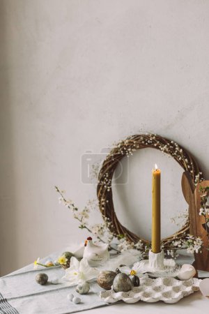 Photo for Happy Easter! Stylish easter eggs, wooden bunnies, cherry blossom and candle on rustic table. Modern natural dyed marble eggs and spring flowers. Easter still life decor in countryside home - Royalty Free Image