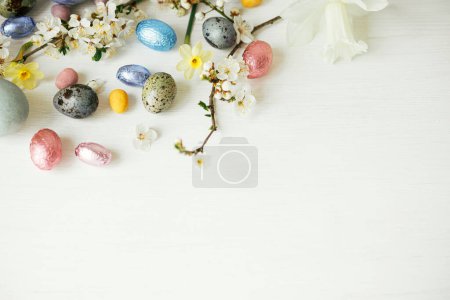 Photo for Easter flat lay. Stylish easter eggs and cherry blossom on white rustic table. Happy Easter, space for text. Modern natural dyed and chocolate eggs and spring flowers. Easter minimal banner - Royalty Free Image