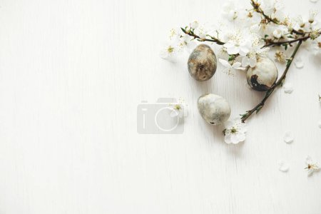 Photo for Easter flat lay. Stylish easter eggs and cherry blossom on rustic white table. Happy Easter! Minimal easter border template with space for text. Modern natural dye marble eggs and spring flowers - Royalty Free Image