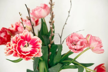Téléchargez les photos : Beau bouquet de tulipes et de branches de saule en vase. Joyeux Pâques ! Décor de table de Pâques simple dans le salon de la ferme - en image libre de droit