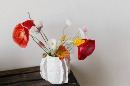 Stylish summer bouquet on rustic wooden bench. Beautiful red and yellow poppies in modern vase. Summer wildflowers, floral still life. Happy Mothers day, space for text