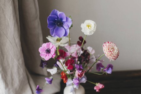 Photo for Summer flowers in vase, rustic still life. Beautiful colorful anemone, ranunculus, lathyrus on aged wooden bench with linen curtains. Floral moody wallpaper. Space for text - Royalty Free Image