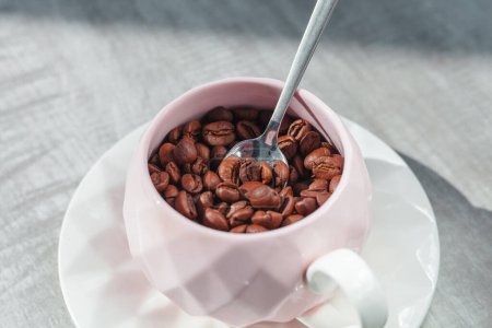 Téléchargez les photos : Grains de café dans la tasse sur l'assiette avec cuillère sur la table - en image libre de droit
