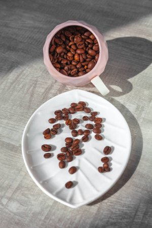 Téléchargez les photos : Grains de café en tasse tombent sur l'assiette - en image libre de droit