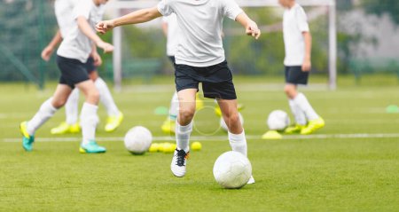 Photo for Children on Soccer Training. Group of Young Boys Kicking Football Balls on Grass Field. Anonymous Group of Kids practicing Soccer at School Field - Royalty Free Image