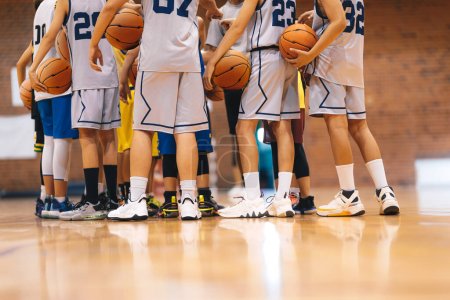 Photo for Junior Basketball Team During Training Class Standing Together and Huddling in Circle. Players Listening to Coaches' Motivational Speech Before The Game. Men's College Basketball Team at Tournament - Royalty Free Image