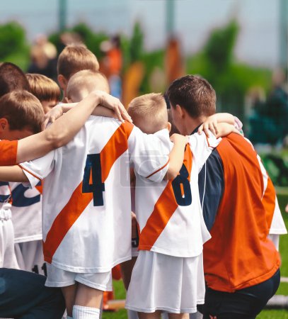 Photo for Kids With Coach in Sports Team. Friends on a Soccer Team. Male Football Players Huddling Together in a Circle Before a Match - Royalty Free Image