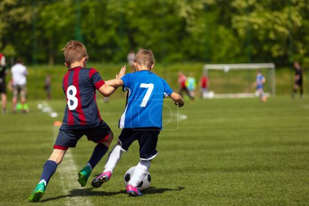 Photo for Young Players in Sports Duel. Two School Boys Playing a Competitive Soccer Football Game.Kids Kicking the Ball During Junior Soccer League - Royalty Free Image