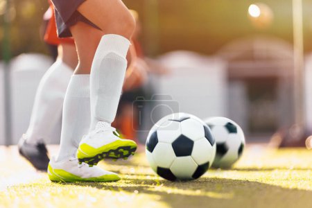 Photo for Football Player Kicking Ball on Sunny Day. Soccer Boy Running in White Cleats on Grass Pitch. Sports Soccer Low Angle Background - Royalty Free Image