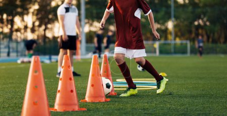 Photo for Soccer Training Class. Legs of Children on Football Lesson. Kids Practicing Soccer Skills on School Grass Field. Boy Running Next to Orange Training Cone in Practice Drill - Royalty Free Image