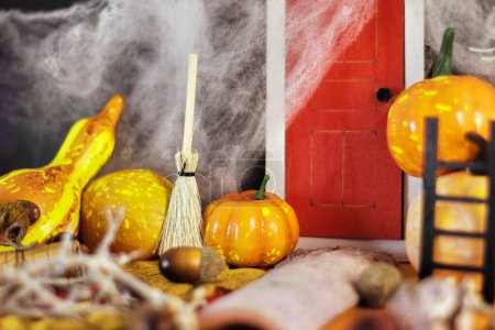 Photo for Spooky Halloween party decorations featuring a red door surrounded by cobwebs, pumpkins, and a mysterious broom, set against a dark background. Get ready for the Halloween festivities with this eerie scene. Perfect for your Halloween-themed projects - Royalty Free Image