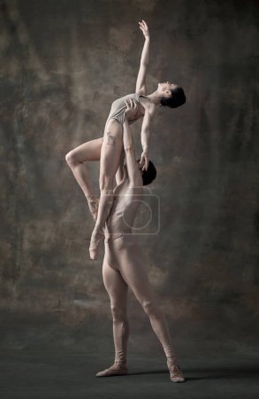 Photo for Young man and woman, ballet dancers performing isolated over dark green vintage background. Holding high. Grace. Contemporary ballet. Concept of classic dance, artist, beauty. Copy space for ad - Royalty Free Image