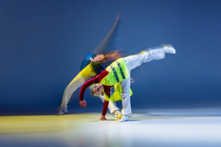 Foto de Retrato de un joven bailando aislado sobre fondo azul oscuro con luces mixtas. Trucos de hip-hop. Concepto de movimiento, cultura juvenil, estilo de vida activo, acción, danza callejera, anuncio - Imagen libre de derechos