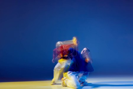 Foto de Retrato de un joven bailando aislado sobre fondo azul oscuro con luces mixtas. Hip-hop. rhytm. Concepto de movimiento, cultura juvenil, estilo de vida activo, acción, danza callejera, anuncio - Imagen libre de derechos