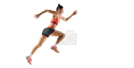 Foto de Atleta en movimiento. Vista de perfil de la joven chica deportiva fitness en runnin uniforme deportivo, entrenamiento aislado sobre fondo blanco. Movimientos dinámicos, técnica de carrera. Copiar espacio para anuncio - Imagen libre de derechos