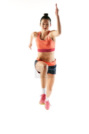 Photo for Front view. Athlete in motion. Young fitness sportive girl in sports uniform running, training isolated over white background. Dynamic movements, running technique. - Royalty Free Image