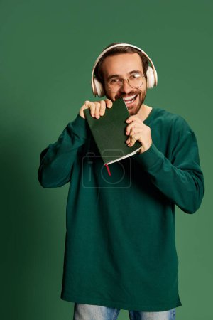 Photo for Hard working. Young handsome happy man with beard wearing casual sweater and glasses over green background. Happiness, positive emotions. Monochrome - Royalty Free Image
