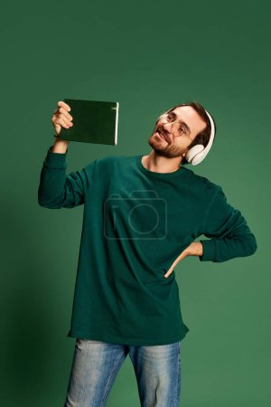 Photo for Portrait of young handsome happy man with beard wearing casual sweater and glasses over green background. Happiness, positive emotions. Monochrome - Royalty Free Image