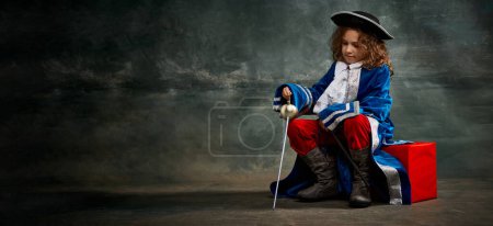 Photo for Banner with serious thoughtful little girl wearing costume of prince, musketeer posing over dark vintage style background. Fashion, theater, beauty, emotions concept. Eras comparison - Royalty Free Image