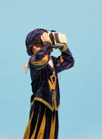 Photo for One little boy in costume of medieval pageboy, little prince wearing VR headset standing over blue background. Emotions, virtual reality, games, dreams concept. Copyspace for ad - Royalty Free Image