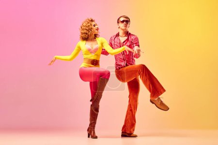 Photo for Disco style. Young emotional man and woman, professional dancers in retro clothes dancing dance over pink-yellow background. American culture, 1970s, 1980s fashion, music concept - Royalty Free Image