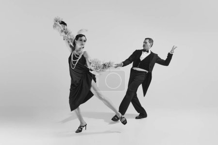 Retro man and charming woman in old-time evening chic outfits having fun together. Concept of love and music, temptation and fashion, rich people party concept, american culture, performance