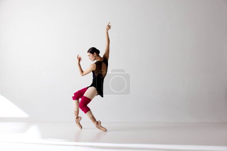 Photo of gorgeous ballerina wearing pointe shoes dancing on fingertips over white background. The art, artist, movement, action and motion concept. Beauty of contemporary dance