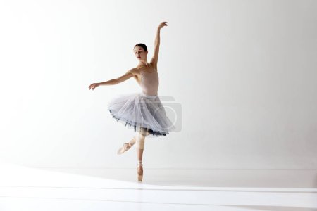 Solo performance. Shot of one adorable ballerina dancing with elegance hands over white background. The art, artist, movement, action and motion concept. Beauty of ballet