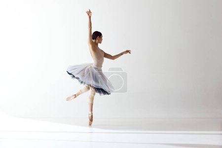 Ballerina Dance. One beautiful ballet dancer dancing with gracual hands over white background. Art, motion, action, flexibility, inspiration concept. Beauty of contemporary dance