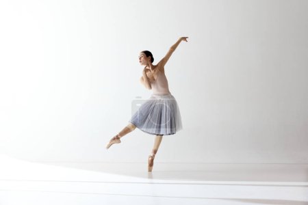 Graceful ballerina, ballet. Beautiful woman ballet dancer dancing over white background. Art, motion, action, flexibility, inspiration concept. Beauty of contemporary dance