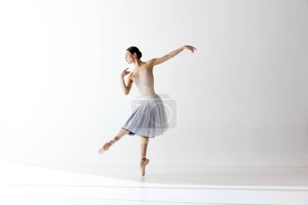 Graceful ballerina, ballet. Beautiful woman dancer dancing over white background. Art, motion, action, flexibility, inspiration concept. Beauty of contemporary dance