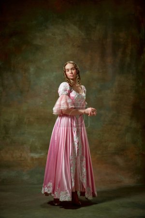 Photo for Elegant lady. Portrait of beautiful blond girl, princess wearing fancy pink dress and standing with folded hands over vintage texture background. Concept of medieval, beauty, old-fashioned clothes, ad - Royalty Free Image