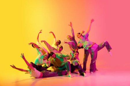 Vielfalt, Chaos und Freiheit. Eine Gruppe junger Leute, tanzende Mädchen, wetteifern vor rosa und gelben Gradienten-Hintergrund in Neonlicht. Modern Freestyle Dance, zeitgenössische Kunst, Bewegungen, Hobbykonzept