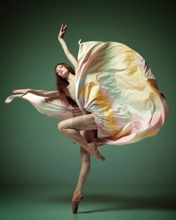 Foto de Ballet moderno con vestido de seda. Una bailarina adorable, niña bailando con elegancia con tela sobre fondo de estudio verde oscuro. Concepto de belleza arte clásico del ballet, estética - Imagen libre de derechos