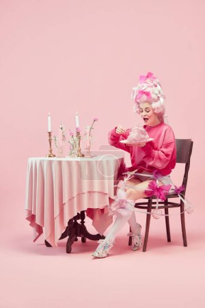 Photo for Sweet cotton breakfast. Portrait of elegant princess, queen wearing elegant clothes and wig eating over pink background. Concept of comparison of eras, modernity and renaissance, beauty, history - Royalty Free Image