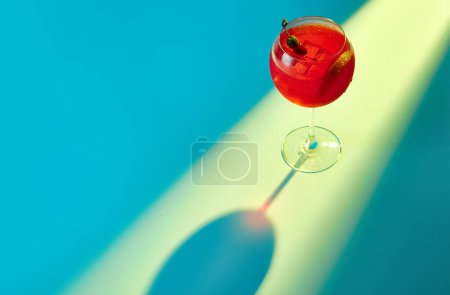 Foto de Vibrante retrato con vidrio de Aperol Spritz sobre fondo de neón azul claro. Bebida alcohólica a base de Prosecco, cubitos de hielo y naranjas. Luz mixta. Concepto de celebración, bar, anuncio - Imagen libre de derechos