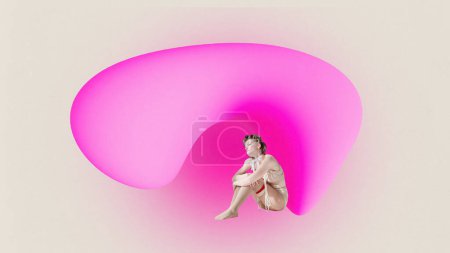Horizontal picture of upset young woman sitting with knees bent under bright pink figure. Concept of mood, lifestyle, abstract, people and ad.