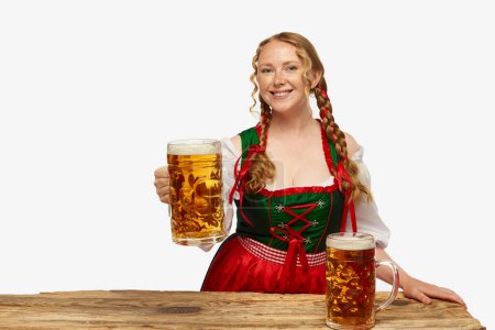 Photo for Bavaria. Smiling young girl wearing traditional Bavarian or german dirndl, holding huge beerglasses over white background. Concept of Oktoberfest, traditions, drinks and food. Copy space for ad. - Royalty Free Image