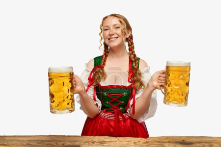 Photo for Festival. Smiling young woman dressed traditional Bavarian or german dirndl, holding huge beerglasses over white background. Concept of Oktoberfest, traditions, drinks and food. Copy space for ad. - Royalty Free Image