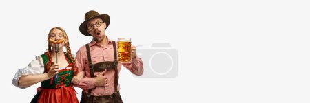 Photo for Full lenght portrait of friendly man and woman wearing folk festival outfits with Bavarian beer glasses and tasty sausages. Concept of alcohol, traditions, holidays, festival. Copy space, ad, banner - Royalty Free Image