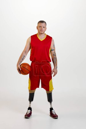 Photo for Attractive young man amputee with prosthetic leg disability standing holding orange basketball ball. Inclusive sport for people with disabilities. concept of sport, player, medical, health, body care. - Royalty Free Image