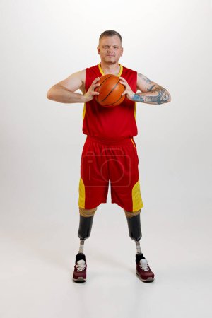 Photo for Attractive man with prosthetic leg disability standing holding orange basketball ball. Inclusive sport for people with disabilities. concept of sport, player, medical, health, body care. - Royalty Free Image