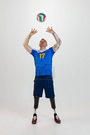 Photo for Attractive young man with prosthetic leg disability standing throws up volleyball ball. Inclusive sport for people with disabilities. concept of sport, player, medical, health, body care. - Royalty Free Image
