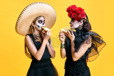 Photo for Happy halloween. Trick or treat. Mother and daughter in spooky makeupeating delicious hot pizza against bright yellow background. Concept of holidays, party, horror, celebrations, food. ad - Royalty Free Image