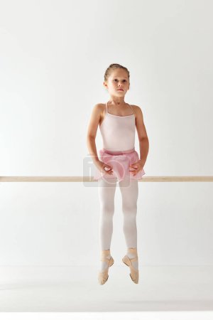 Téléchargez les photos : Vue arrière portrait de petite danseuse ballerine adorable en robe de ballet tutu rose sur pointe posant et exécutant des éléments de danse. Cours d'éducation. Concept de beauté, mode, passe-temps, action. - en image libre de droit