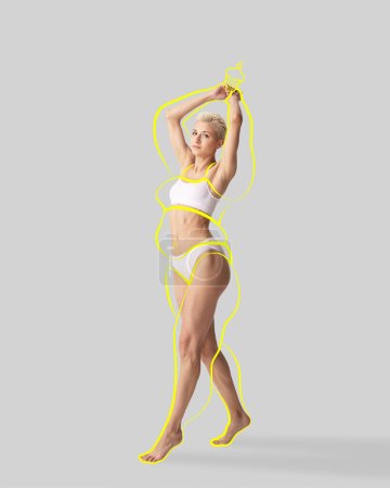 Sensual mujer de pelo corto en lencería blanca con silueta de cuerpo amarillo dibujado alrededor del cuerpo con comida posando sobre fondo de estudio. positividad corporal. Concepto de alimentación saludable, dieta, cuidado corporal, deporte