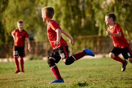 Photo for Full length side view portrait of kids, football players in sport uniform training, running at speed in motion before match on soccer field on sunny summer day. Concept of sport workout, activity. - Royalty Free Image