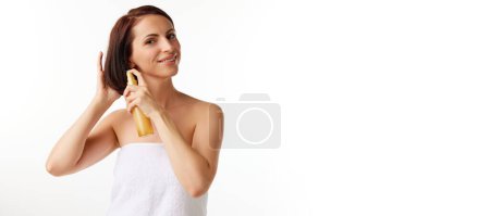 Photo for Young beautiful brunette woman applying hair spray on her hair, enjoying new hairstyle cosmetics and smiling over white color studio background. Beauty routine, cosmetology, youth concept - Royalty Free Image