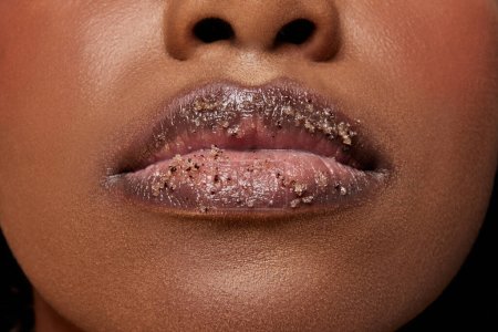 Vista de cerca de la mujer afroamericana con los labios cubiertos de azúcar. Exfoliar el tratamiento de spa para los labios. Concepto de belleza, maquillaje, cosmetología, tratamientos de spa, productos cosméticos. Anuncio