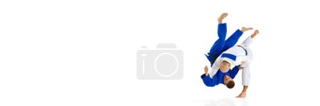 Téléchargez les photos : Bannière. Deux hommes judoistes formation, combats montrant la compétence technique isolé fond studio blanc. Concept d'art martial, sport de combat, santé, force, énergie, forme physique. Espace de copie - en image libre de droit